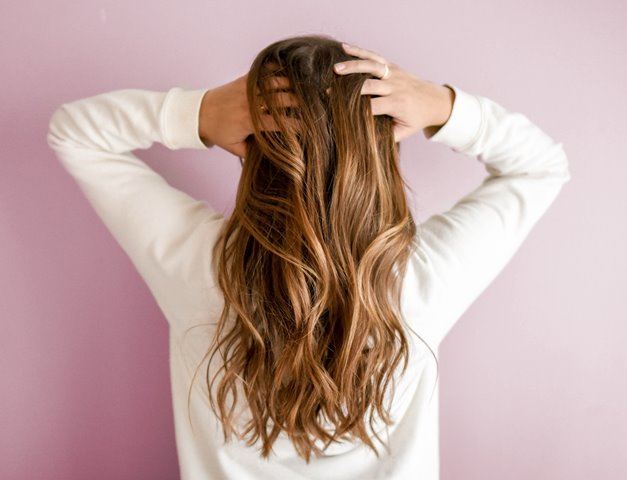 Mulher de costas com a mão no cabelo